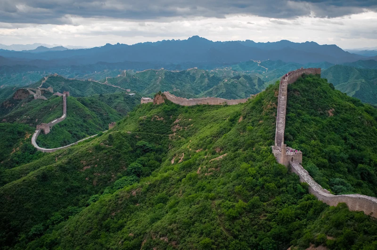 The Great Wall of China running along a ridgeline at Jinshanling, watchtowers stepping away over the hills into haze.