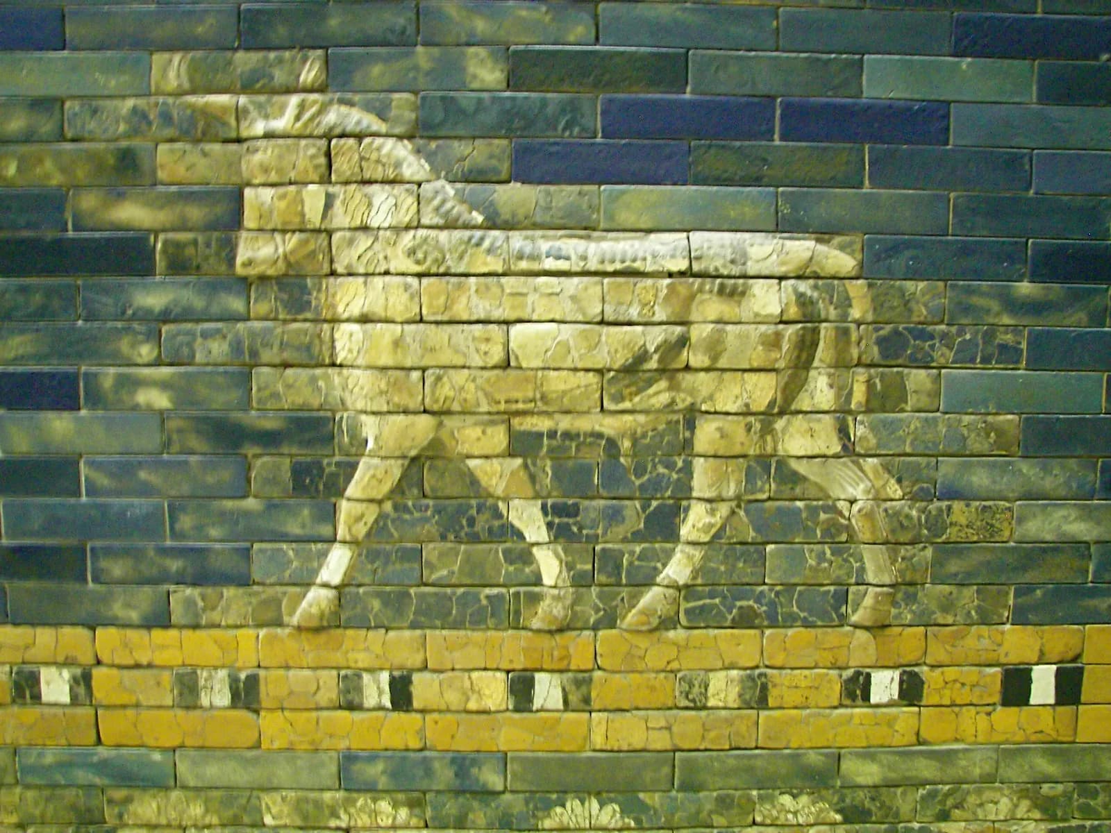 The reconstructed Ishtar Gate of Babylon in the Pergamon Museum — a monumental arched gateway faced in lapis-blue glazed brick, ranked with reliefs of bulls and dragons.