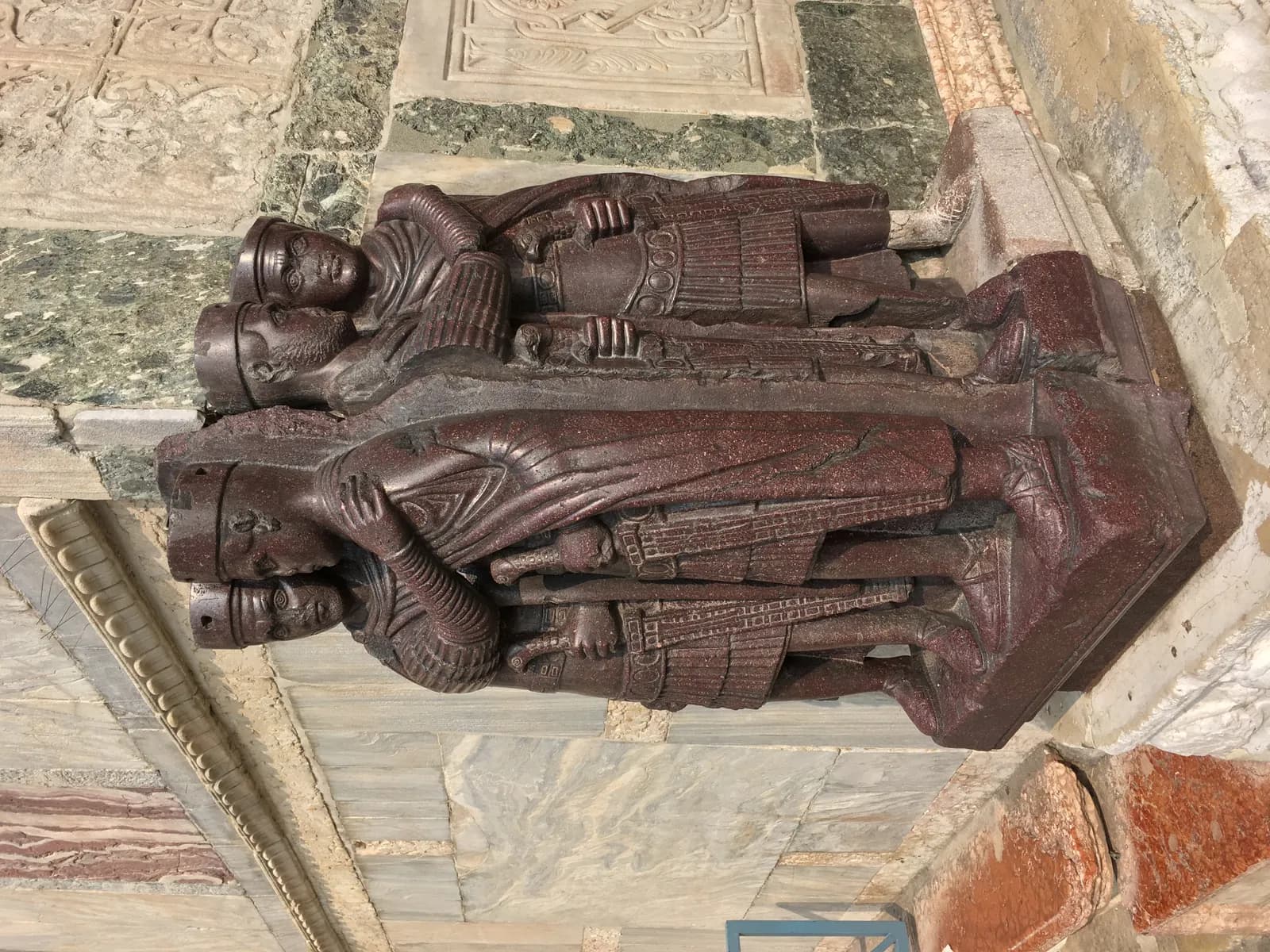 The porphyry Portrait of the Four Tetrarchs, c. 300 CE, set into the corner of St Mark's Basilica in Venice — the two Augusti and two Caesares of Diocletian's tetrarchy shown as identical, embracing, abstract figures of imperial office rather than individuals.
