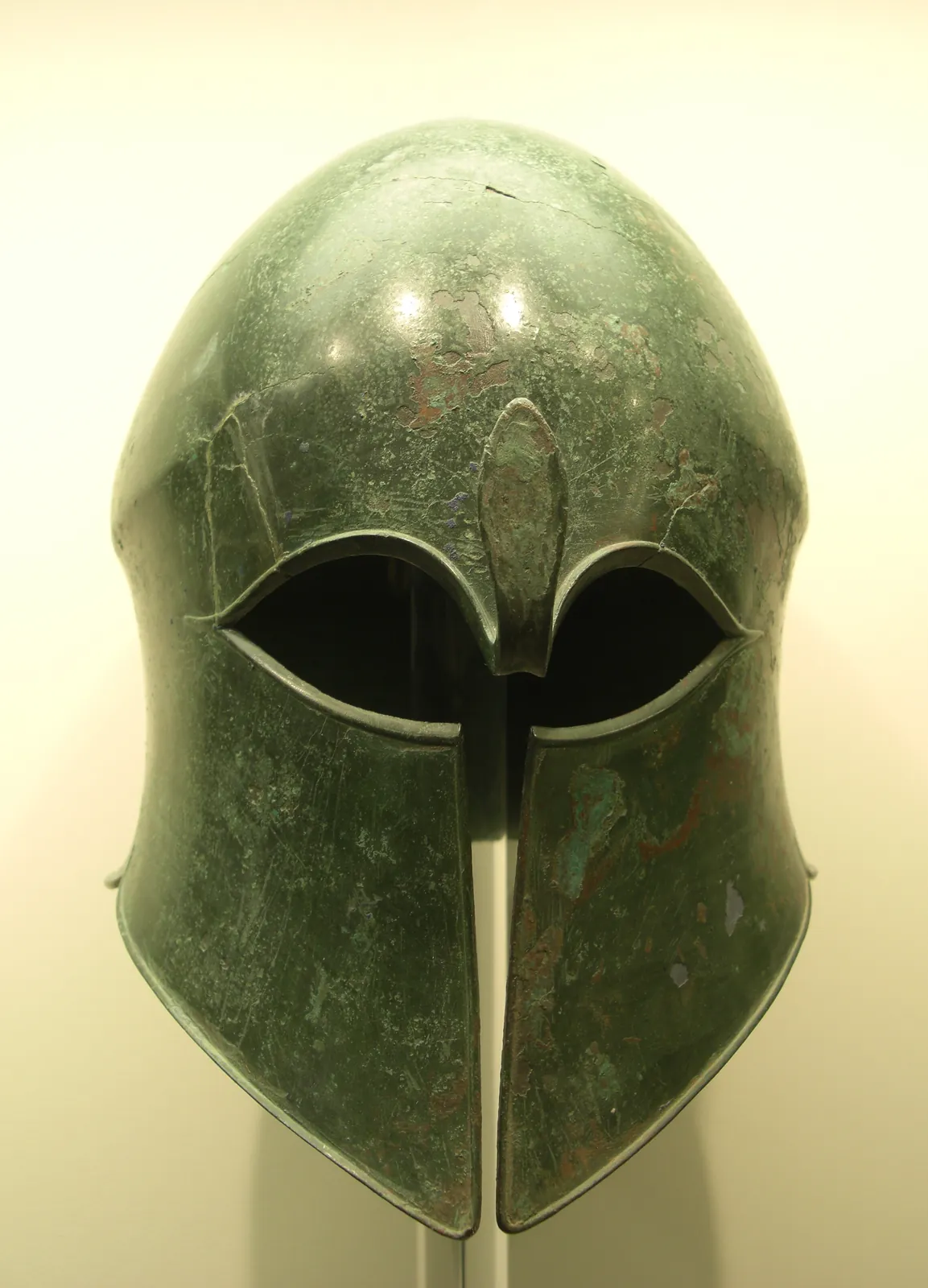 Bronze helmet beaten from a single sheet, enclosing the whole head with a narrow eye slit and a fixed nose guard.