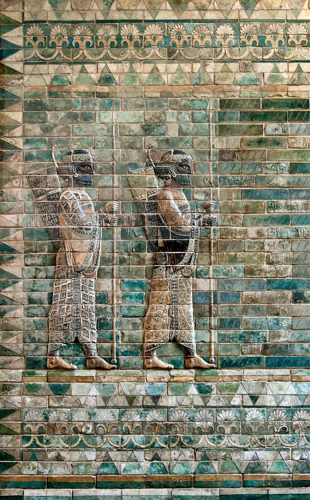 Panel of moulded and glazed brick showing a guardsman in a patterned robe carrying a spear, bow and quiver.