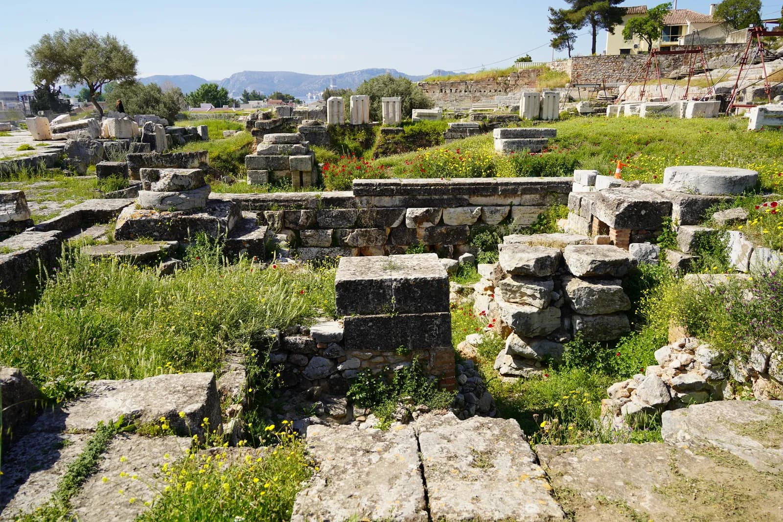 A wide rock-cut platform with rows of steps cut into the hillside along one side and square column bases across the floor.