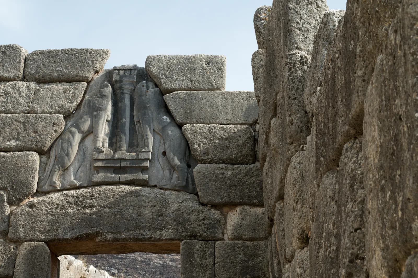 Monumental stone gateway with a triangular relief above the lintel showing two facing animals flanking a column.