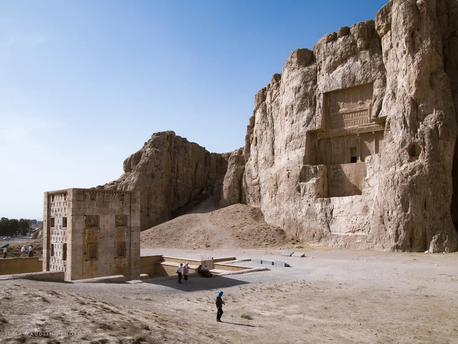 The cliff face at Naqsh-e Rustam with the cross-shaped rock-cut façades of the Achaemenid royal tombs, traditionally those of Darius I and his successors, above later Sasanian reliefs.